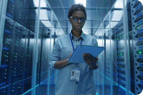 person in a server room with a tablet